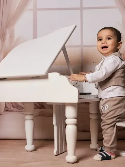 A little boy enjoying his turn at the white piano.