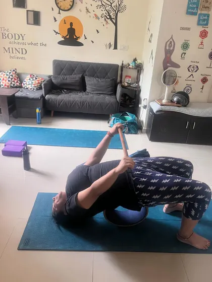 A client uses a stability ball and a strap for a supported bridge pose, adding a core challenge to the backbend.