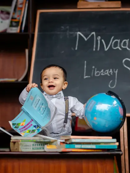 A future world leader in his library. This creative "little scholar" setup includes a chalkboard, books, and a globe for a memorable first birthday shoot.