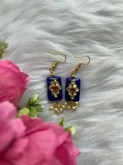 These simple daily wear earrings feature a blue stone, kundan work, and pearl drops. They are budget-friendly and the colours can be customised.