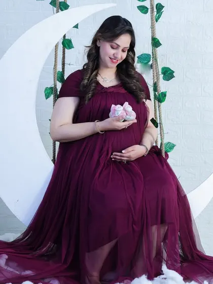 Our moon swing prop surrounded by fluffy clouds makes for a dreamy photo. The deep maroon gown drapes beautifully, adding to the celestial, whimsical feel of the portrait.