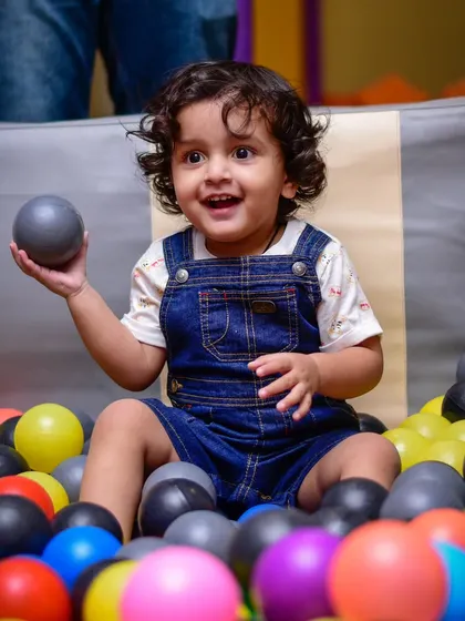 This adorable toddler is having a wonderful time exploring the textures and colors of the ball pit.