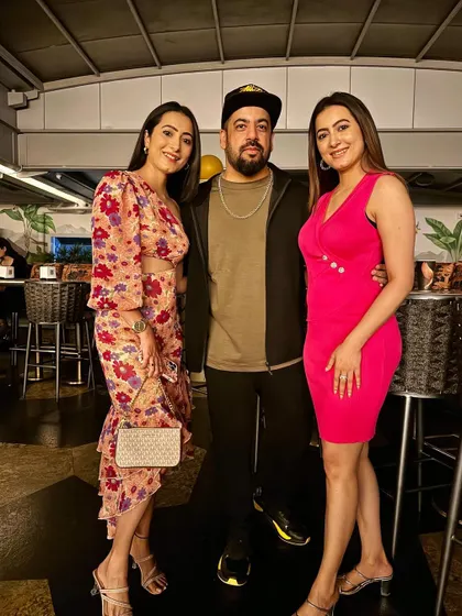 Posing with two stylishly dressed guests, adding a pop of color to the night.