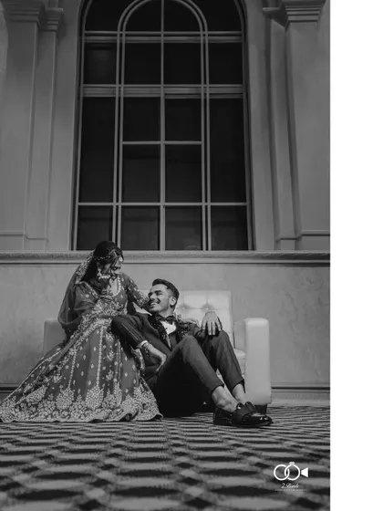 A stunning black and white portrait of the couple relaxing together, the bride seated on the floor leaning against the groom.