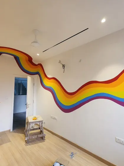 A wide shot of the rainbow mural before the furniture was moved in, highlighting its clean lines and vibrant colors against the white wall.