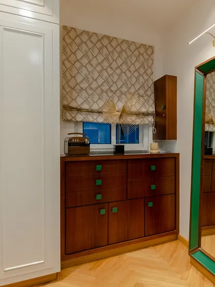 The green handles and mirror frame provide a point of emphasis and a pop of color in this otherwise neutral dressing area.