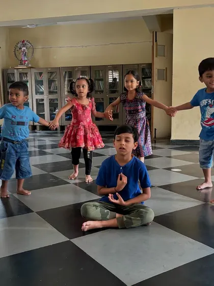 A duplicate of Image 12, showing a young boy in a meditative pose while other children hold hands around him. This image beautifully captures the essence of our camp: finding stillness and connection.