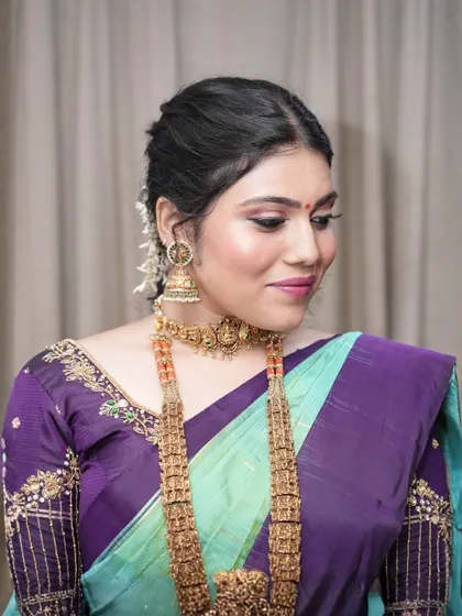 This is a beautiful example of a subtle South Indian look. The makeup is minimal and clean, with a focus on fresh skin, soft pink lips, and gently defined eyes to complement the traditional jewelry.