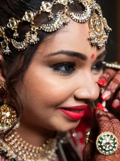 A detailed shot of the bride getting ready, as she carefully puts on her nose ring.