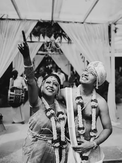 A black and white shot of the couple looking up with joy after a wedding ritual.