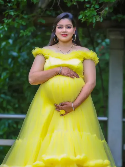 A serene portrait of a mother-to-be in a beautiful yellow off-shoulder gown, surrounded by lush greenery.