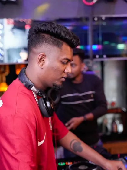 A side profile of me focused on the mixer. I'm always tuned in to the technical details to ensure the sound quality is perfect for the dance floor.