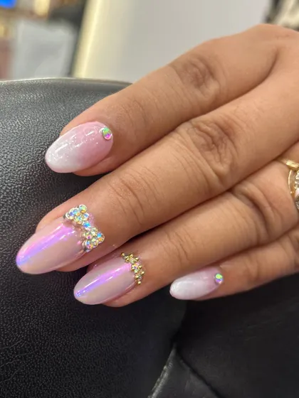 A close-up of the iridescent ombre nail with a hand-placed rhinestone bow. This shows the precision required to create these delicate embellishments that make the design so special.