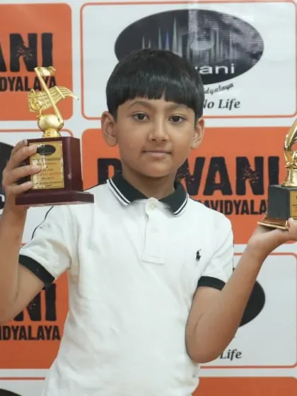 Double the joy! This young achiever holds two trophies from the Dhwani Kala Mahotsav, a testament to his hard work and versatile talent.