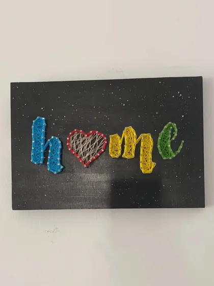 My "Home" string art piece without the lights on. The colorful threads still make it a vibrant and cheerful piece of wall decor.