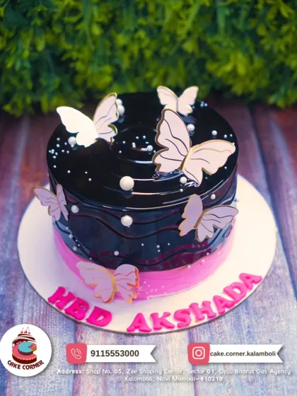 A rich dark chocolate cake decorated with light pink butterflies. The contrast between the dark glaze and the delicate wings is stunning.