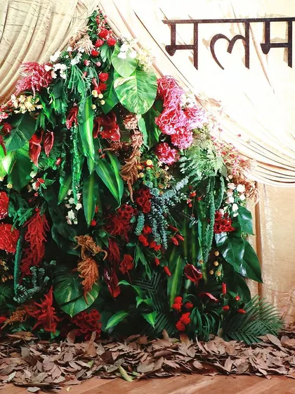 A mountain of tropical leaves and red flowers creates a dramatic and lush photo backdrop for a Diwali collection launch.