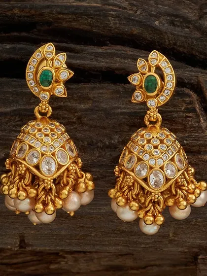 These gold-toned jhumkas are studded with clear stones and feature a crescent-shaped top with an emerald-colored accent. The bell is adorned with clusters of pearls, adding graceful movement.