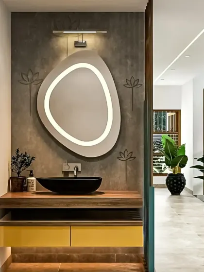 A stylish wash basin unit with a floating wood countertop, a modern black bowl sink, and a unique backlit mirror against a textured grey wall.