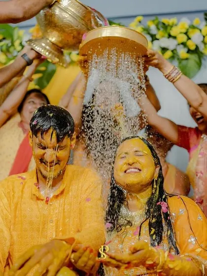 A wider shot of the ritual bath, showing the enthusiastic participation of family and friends. It highlights the communal joy of the celebration.