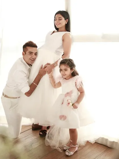 A complete family portrait before the new addition. This shot from a home session shows the excitement of the parents and big sister, all dressed in white for a timeless look.