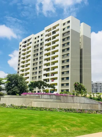 A wide shot of an apartment complex where we designed the surrounding landscape, featuring rolling green lawns and sculpted retaining walls planted with flowers.