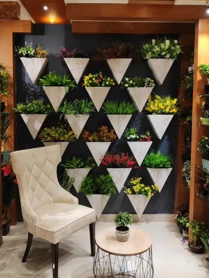 A feature wall with a grid of modern, triangular wall-mounted planters. Each planter is filled with a different type of small artificial plant for a varied and artistic display.