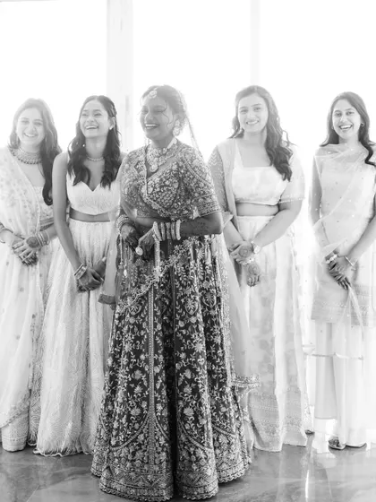 A happy, candid black and white shot of the bride with her bridesmaids, all sharing a laugh.
