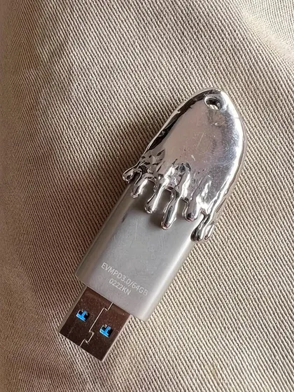 A close-up of the custom silver-capped USB drive. This piece shows how the Frostbite aesthetic can be applied to more than just grillz, turning an everyday object into a unique accessory.