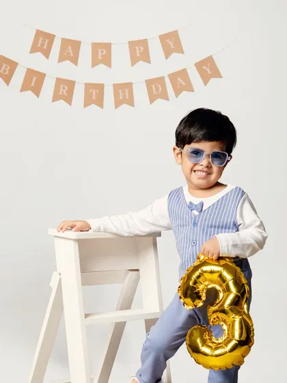 Three cheers for turning three! Dressed in a dapper outfit with a number 3 balloon, this little man is ready to celebrate his third birthday in style against a clean, classic studio backdrop.