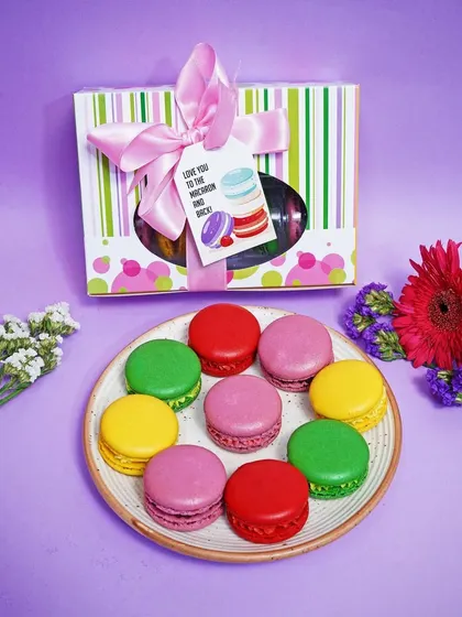 A neat arrangement of colorful macarons on a plate, with the gift box placed behind. This clean, top-down shot is excellent for e-commerce listings and product catalogs.