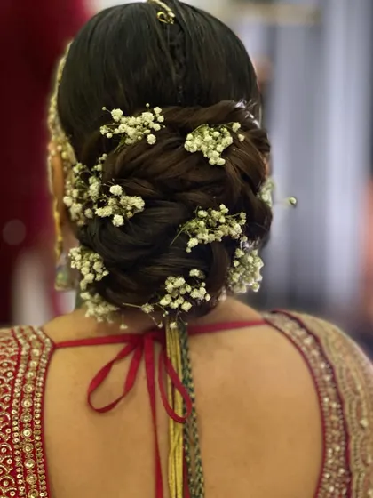 An intricate braided bun decorated with baby's breath. The braiding adds a beautiful texture that is highlighted by the delicate white flowers.