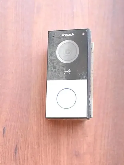 A close-up of a smart video doorbell installed on a wooden door panel, showcasing a clean and modern security solution.