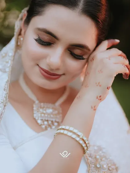 A close-up of a bride's happy and serene face, highlighting her flawless makeup and delicate jewelry.