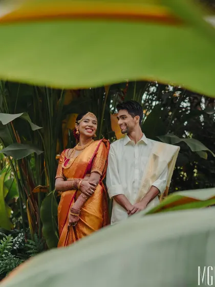 A romantic portrait of the couple framed by lush green leaves. This natural setting provides a beautiful, organic backdrop for capturing their connection after the ceremony.