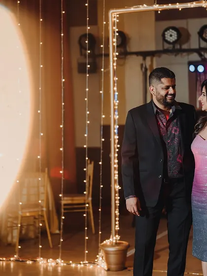 A quiet moment for the couple amidst the celebration, with a backdrop of warm fairy lights creating an intimate and romantic setting.