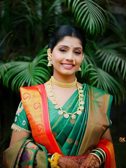 A smiling portrait of the bride in her green and orange silk saree. Her traditional gold jewelry and happy expression make this a timeless and beautiful photograph.