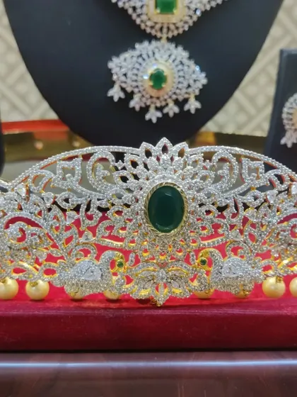 A detailed shot of the intricate vaddanam from the emerald and diamond-look set, featuring swan motifs.