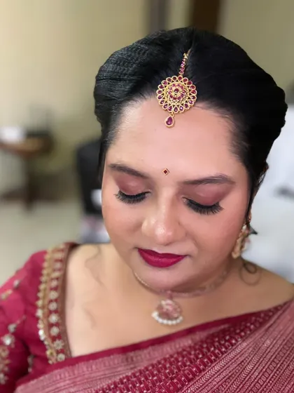 A close up on this beautiful, bold look. The deep berry lip and defined eyes with a touch of shimmer are perfect for an evening function, complementing her maroon saree.
