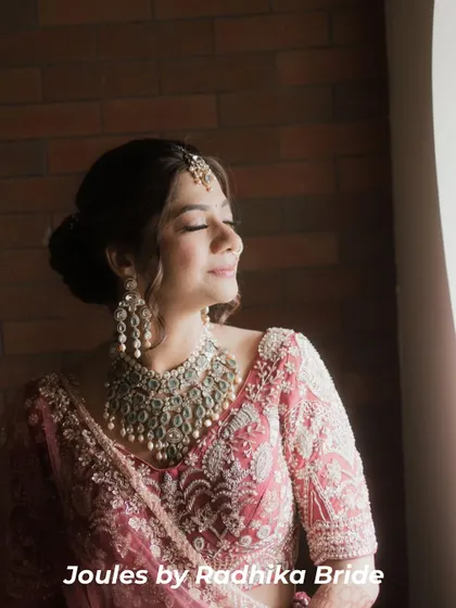 Heritage redefined for the modern bride. This bride is captured in a moment of quiet reflection, wearing an elaborate silver-toned polki set that stands out against her embroidered pink lehenga.