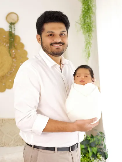 A proud new father holding his swaddled newborn. The soft, natural light creates a warm and gentle portrait.