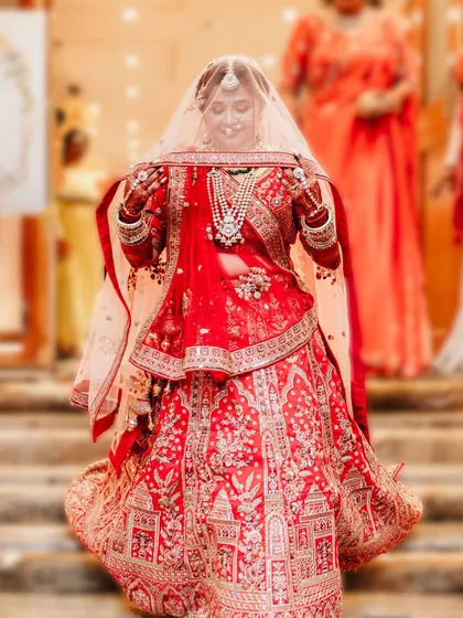 The moment of the bridal entry. The bride looks down shyly under her veil, her intricate red lehenga on full display. This is a classic and timeless shot that every bride treasures.