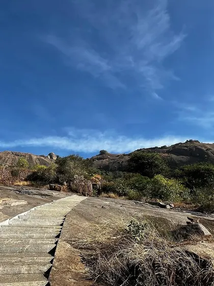 The stone steps of a trail leading up a mountain under a clear blue sky.
