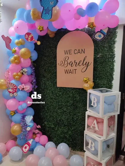 A 'We Can Barely Wait' themed setup against a green hedge backdrop. This popular theme for baby showers features 'BABY' blocks and a pink and blue color scheme for a gender reveal party.