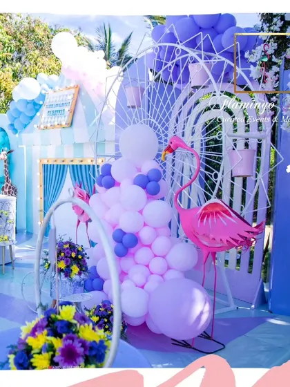 A flamingo-themed section of the carnival party, featuring a pink flamingo prop, a white Ferris wheel, and pink and purple balloon arrangements.