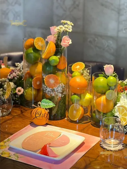This summer birthday tablescape is bursting with freshness, using tall glass vases filled with whole lemons, limes, and oranges, interspersed with delicate floral bouquets.