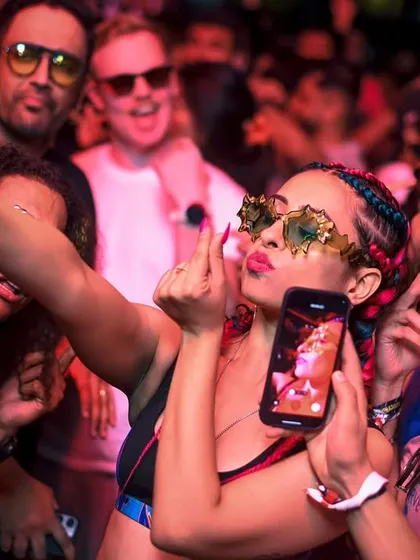 A fan taking a selfie with the party in the background. Capturing the moment.