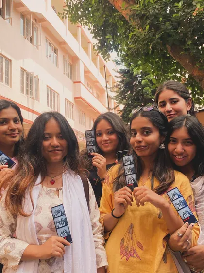 A group of friends showing off their photo strips with a unique pixelated elephant design.