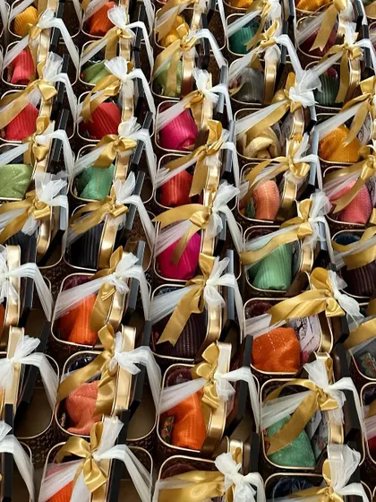 A vibrant array of housewarming return gifts. These metal baskets are filled with colorful blouse pieces and glass bangles, making for a traditional and beautiful favor.