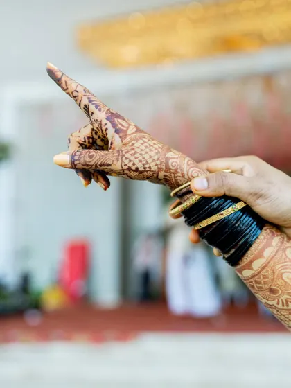 A creative shot focusing on the bride's intricate henna design and traditional bangles.